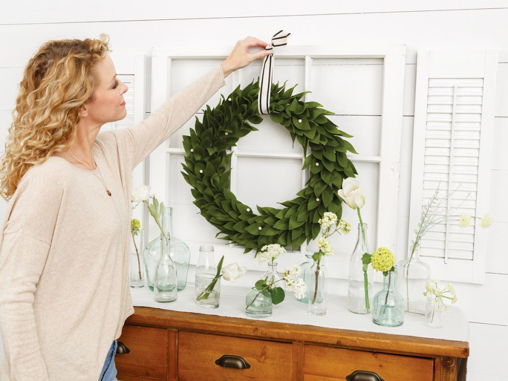 woman hanging up green wreath