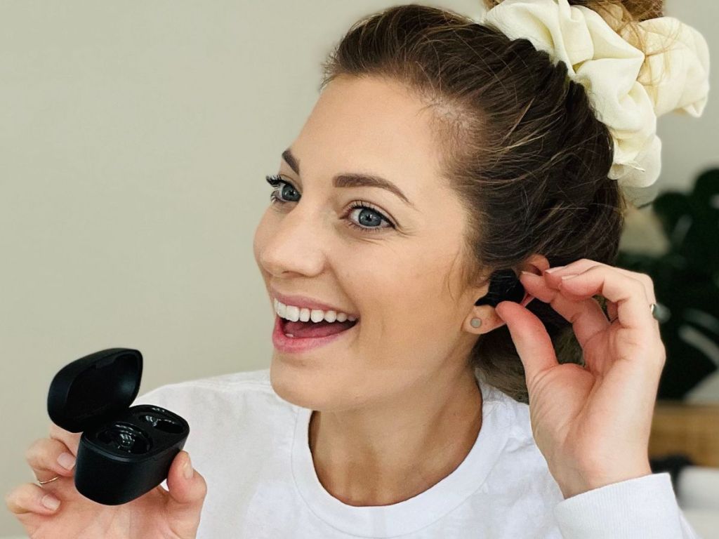 woman wearing Baseus Earbuds while holding the charging case in her hand