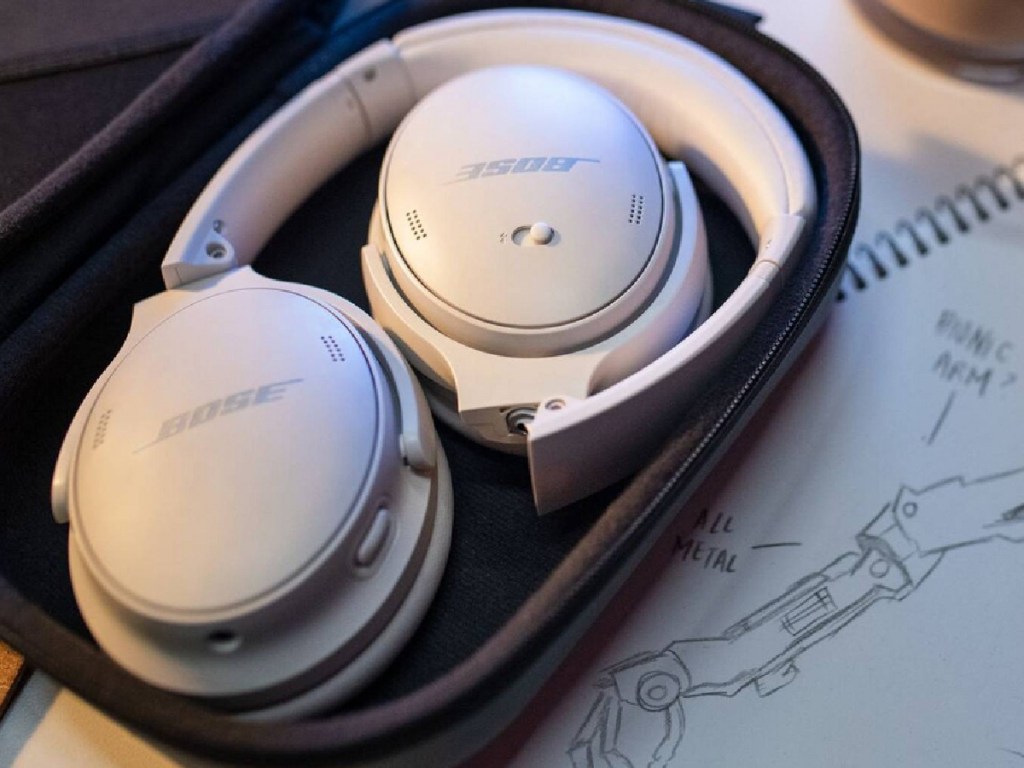 Bose white headsets inside of their case on top of the table