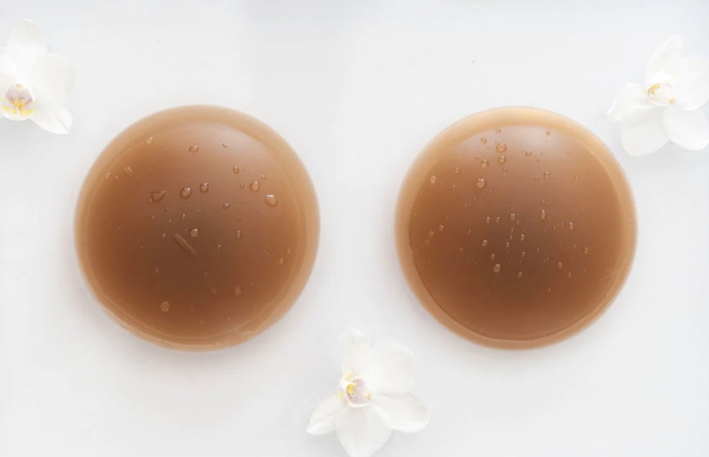 tan colored silicone nipple covers on white surface with flowers and water droplets