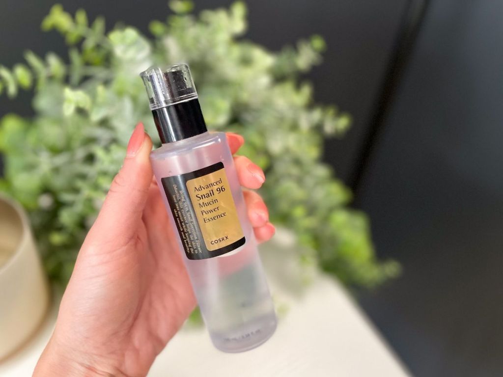 hand holding bottle of COSRX snail mucin power essence