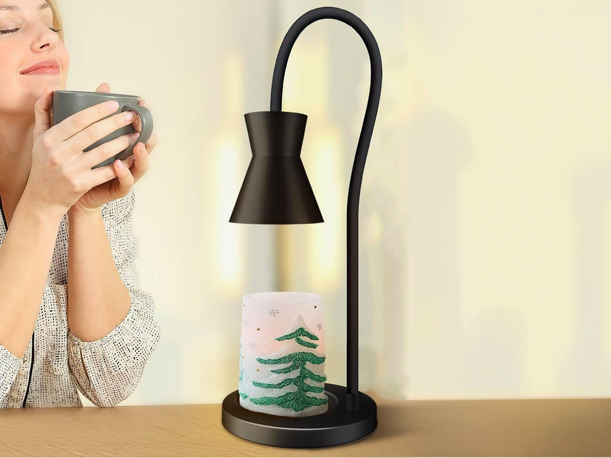 woman smelling a coffee cup in front of a candle lamp