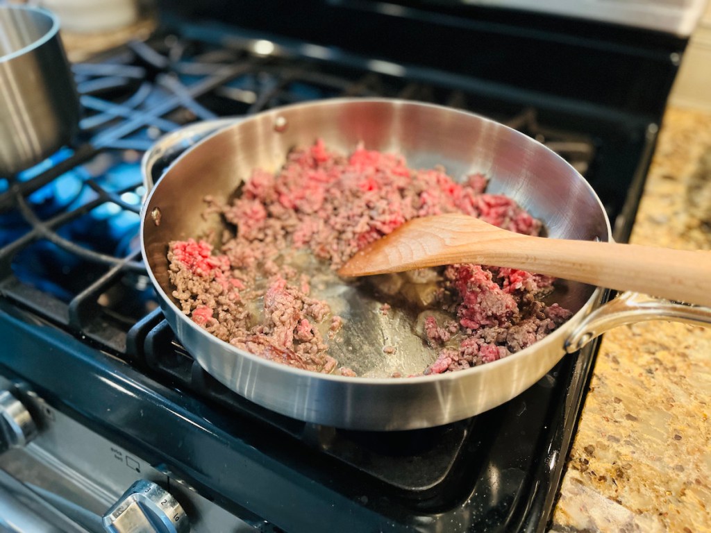 Close-up of stainless steel pan with ground beef cooking on the stove 