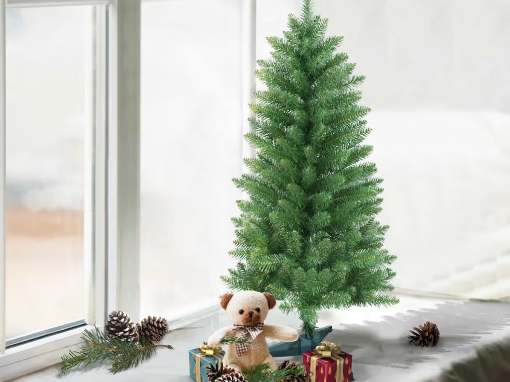 small unlit christmas tree with gifts and bear under it