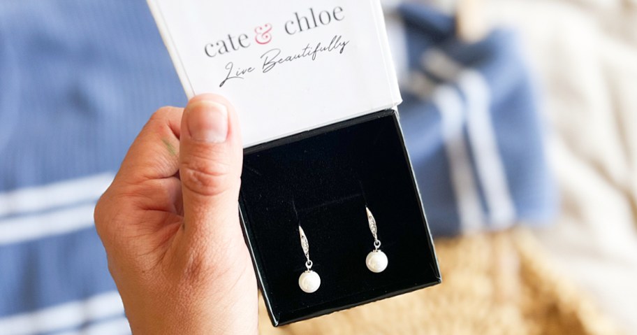 holding up box of pearl earrings