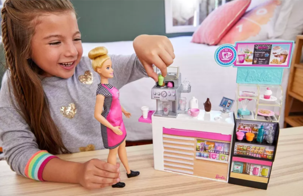 A girl playing with a You Can Be Anything Barbie Doll and her coffee shop