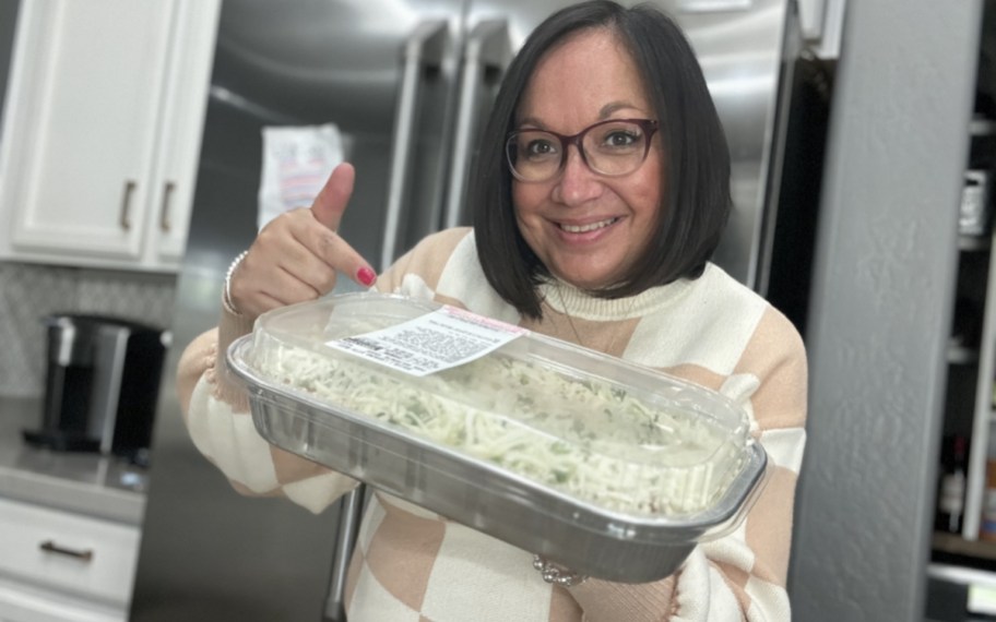woman holding a costco prepared meal of beef ravioli lasagna