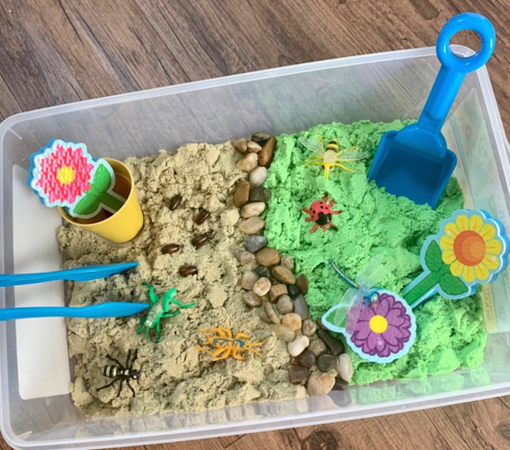 Close up of garden themed sensory bin on wood table
