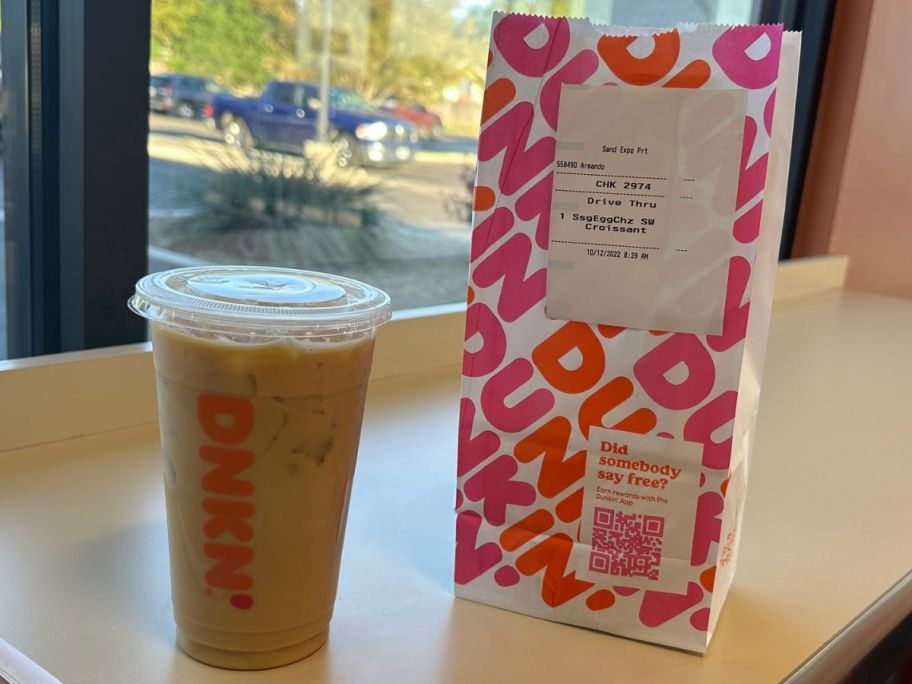A dunkin iced coffee and a bag with a breakfast sandwich in it