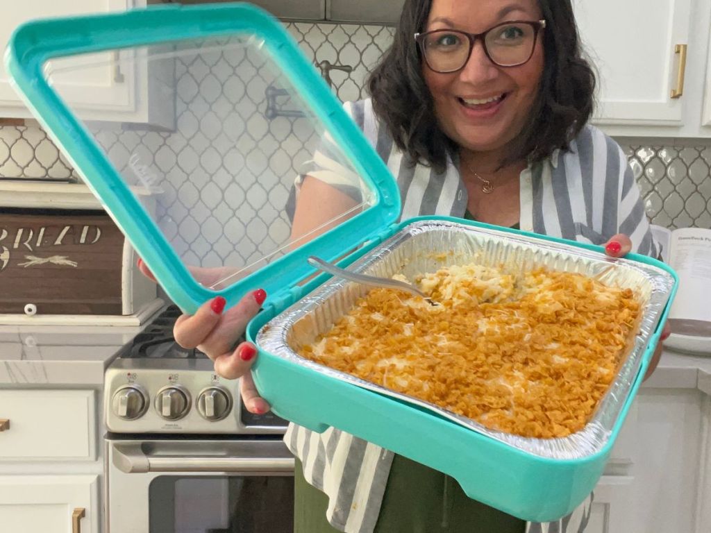 Woman holding a Fancy panz carrier with a tray of cheesy funeral potatoes inside