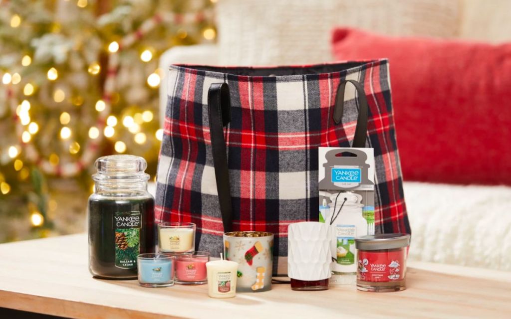Festive fragrance family plaid flannel tote on a table with various Yankee candle items around it