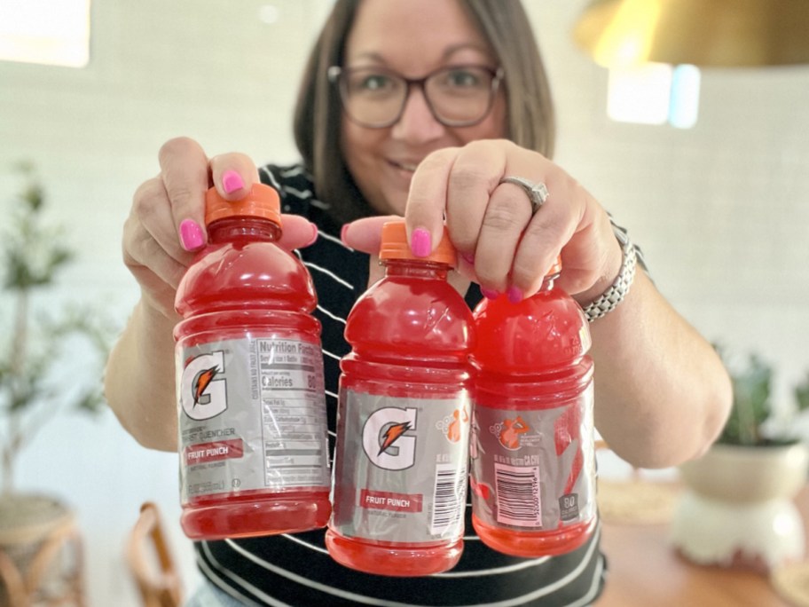 woman holding up three bottles of red gatorade