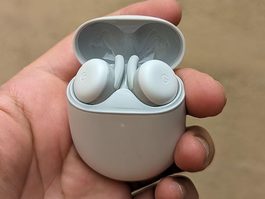 A hand holding a Google Pixel Buds A-Series in white