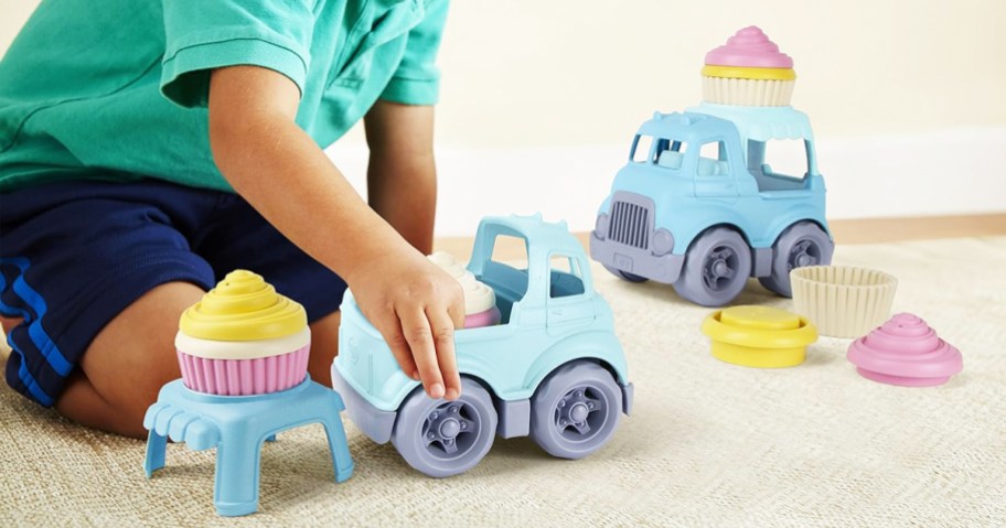 kid playing with blue trucks with cupcakes playset