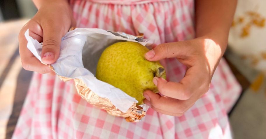 Little girl unwrapping a royal riviera pear from Harry & David