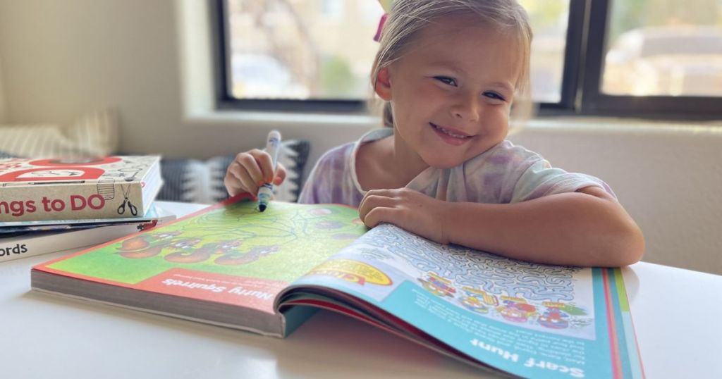 Little girl using a Highlights Jumbo Maze Book