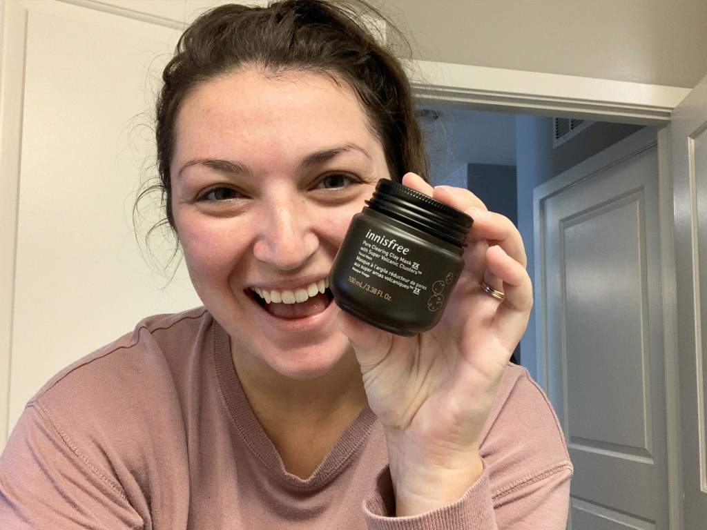 woman holding a jar of Innisfree Pore Clearing Clay Mask