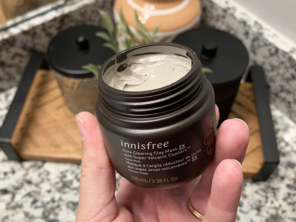 holding a jar of Innisfree Pore Clearing Clay Mask