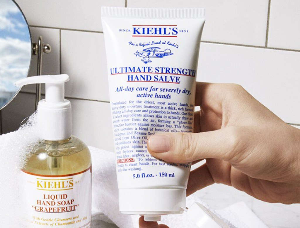 hand squeezing a bottle of Kiehl's Ultimate Strength Hand Salve