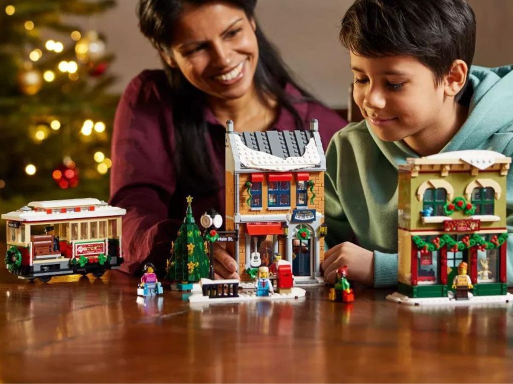 Woman and boy with Lego Holiday Main Street Set constructed in front of them on a table