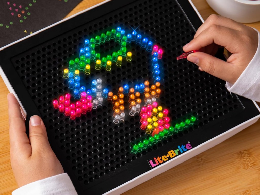 kid playing with lite brite toy