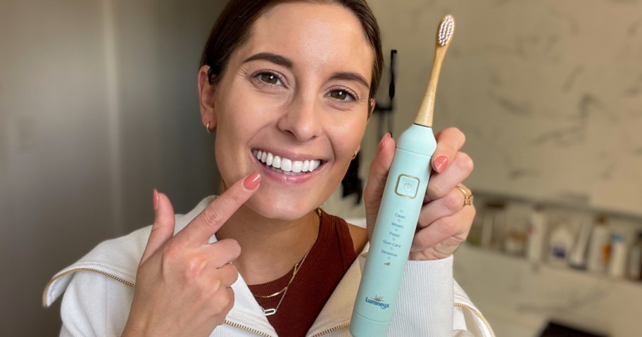 Woman holding a Lumineux Electric Toothbrush