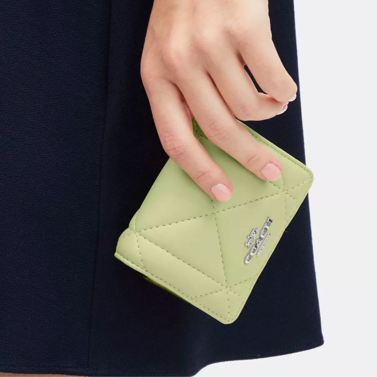 a womans hand holding a coach Mini Wallet On A Chain With Puffy Diamond Quilting in lime