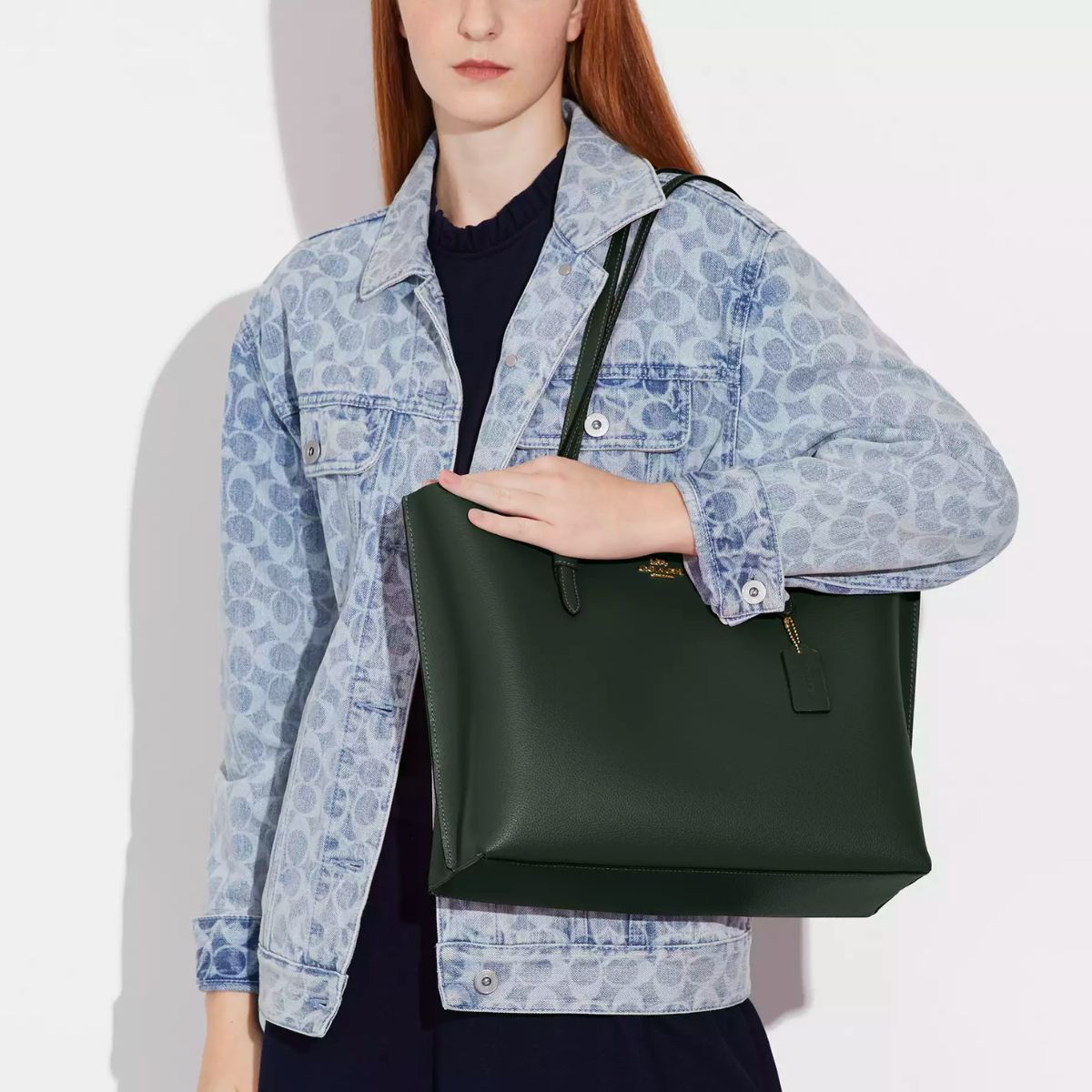 a model wearing a coach Mollie Tote with gold hardware in Amazon Green leather