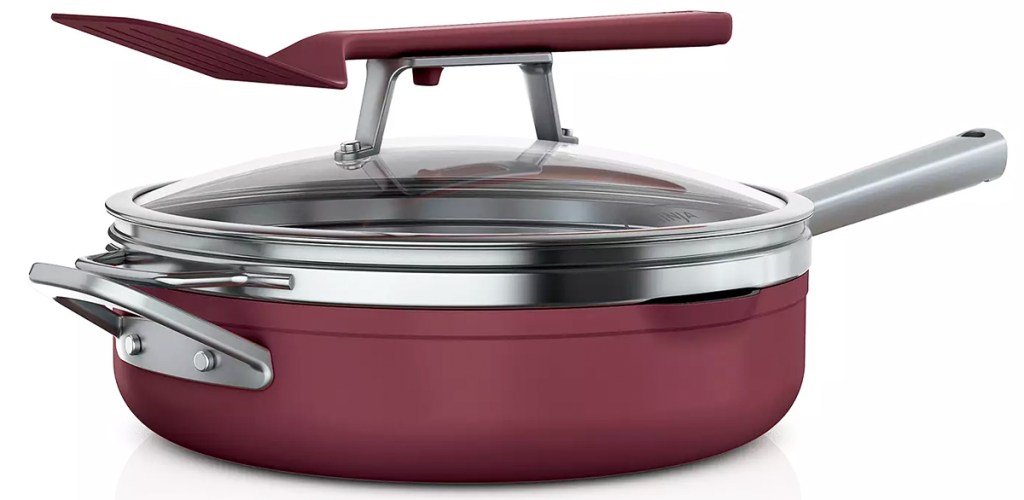 red frying pan with glass lid and utensil on top