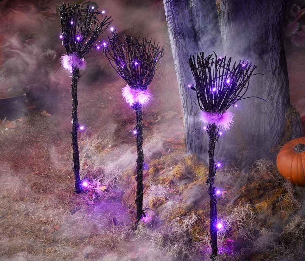 black and purple light up broomsticks stuck in ground