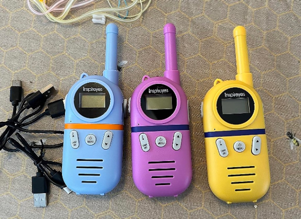 Blue, purple and yellow walkie-talkie laying on countertop with black rechargeable cords