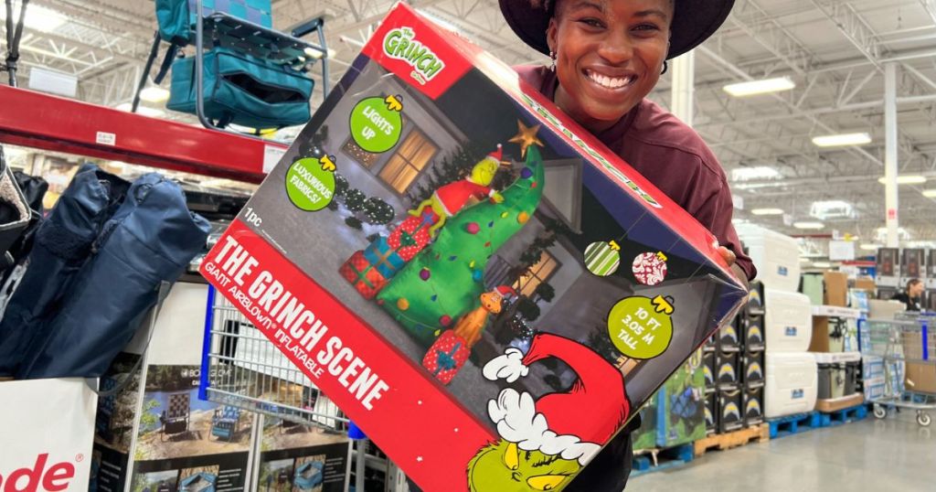 Woman holding box with Sam's club Inflatable Grinch decoration inside