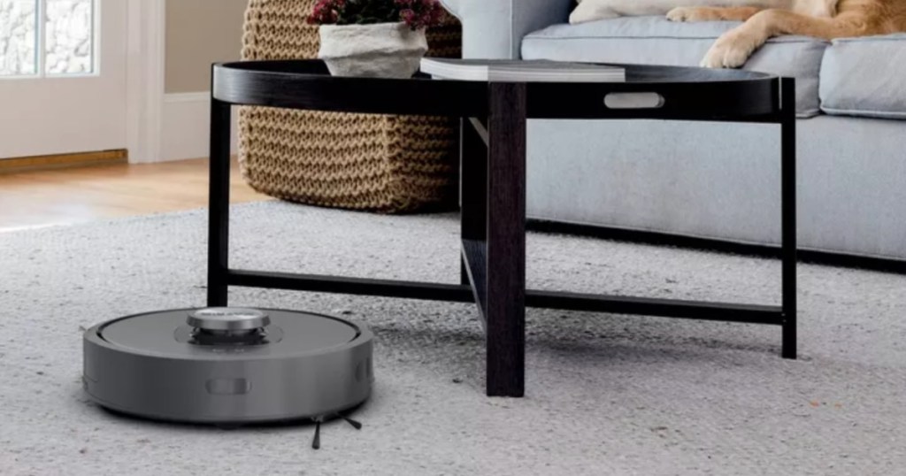 black robot vacuum in front of coffee table