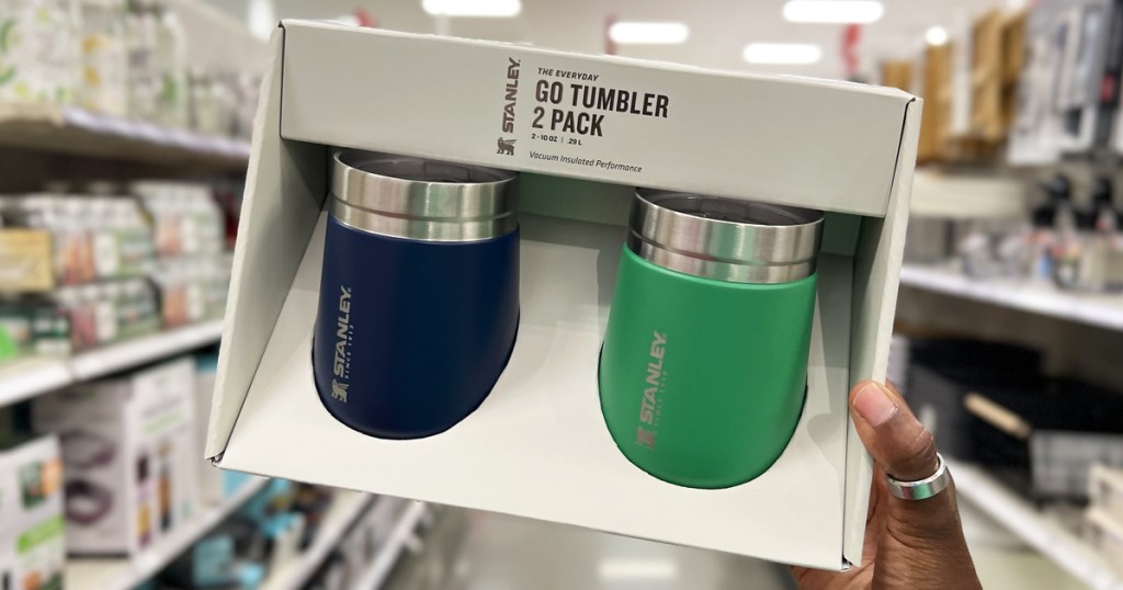 hand holding a set of blue and green stanley drink tumblers
