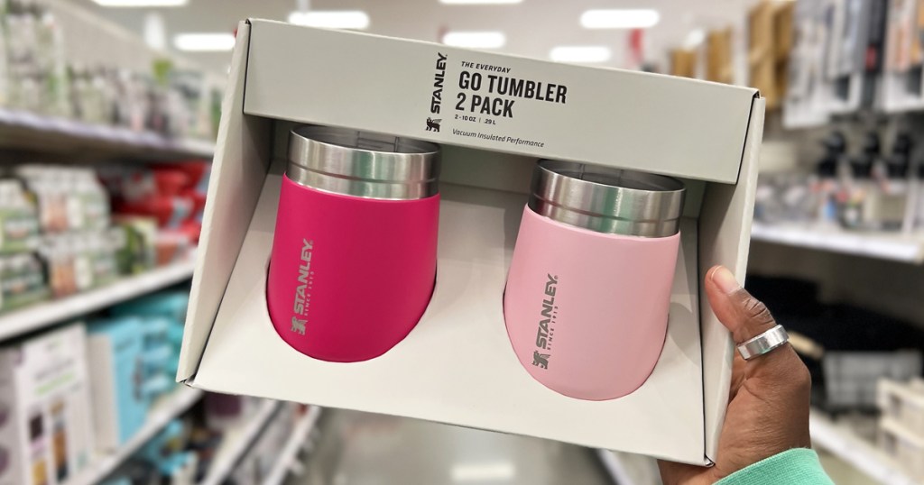 hand holding a set of dark and light pink Stanley drink tumblers