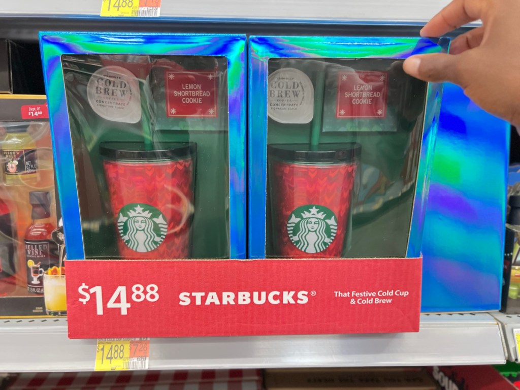 Hand grabbing a Starbucks Cold Brew with tumbler gift set from the Walmart shelf
