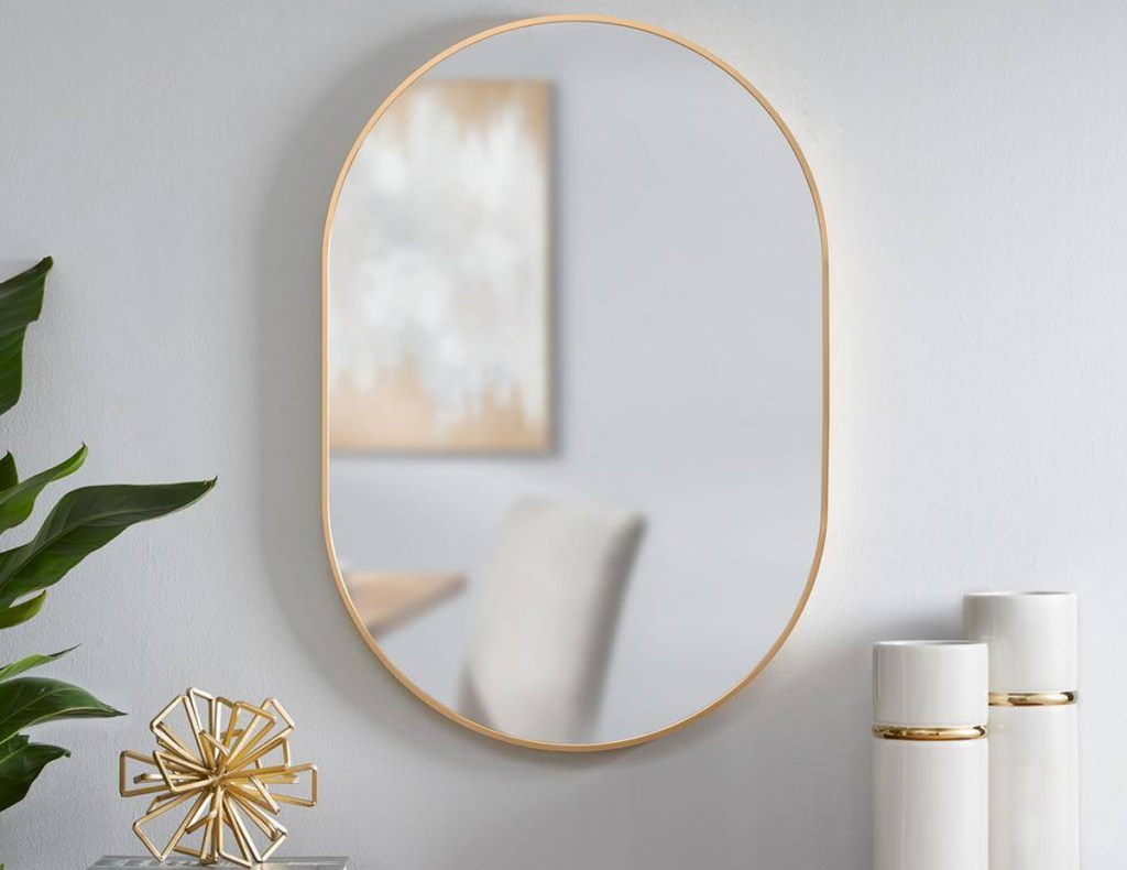 gold framed oval shaped mirror on wall