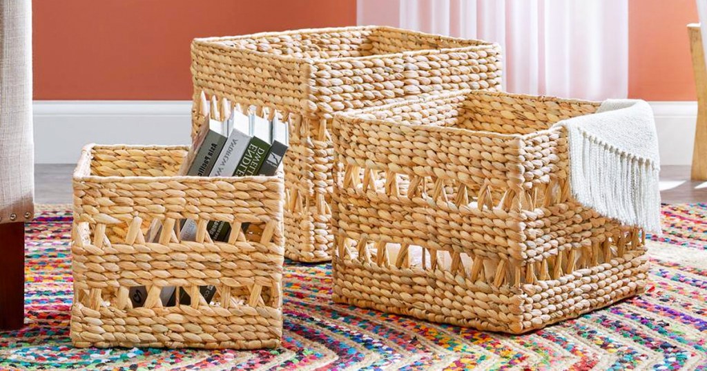 3 wicker storage baskets on floor with books and throw blanket inside