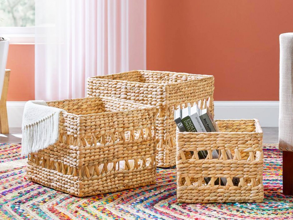 3 wicker storage baskets on floor with books and throw blanket inside
