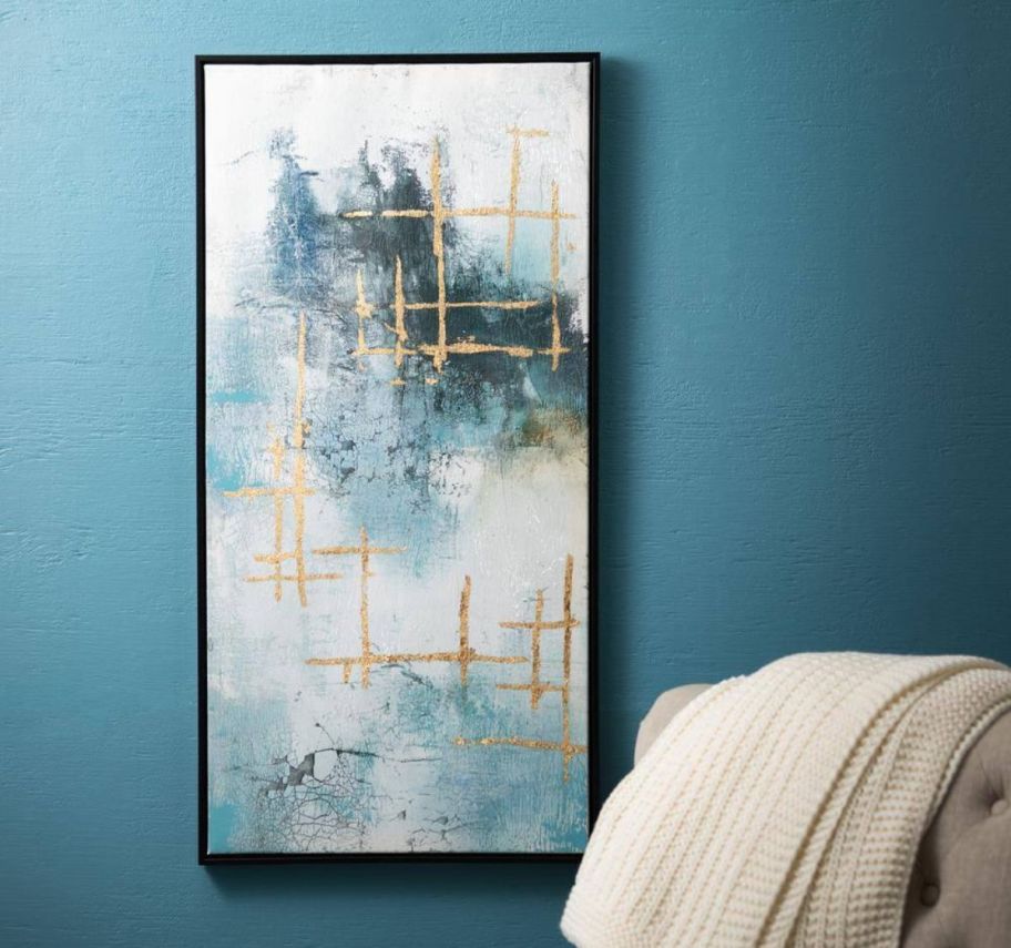 a blue and gold art print on a wall next to an arm chair