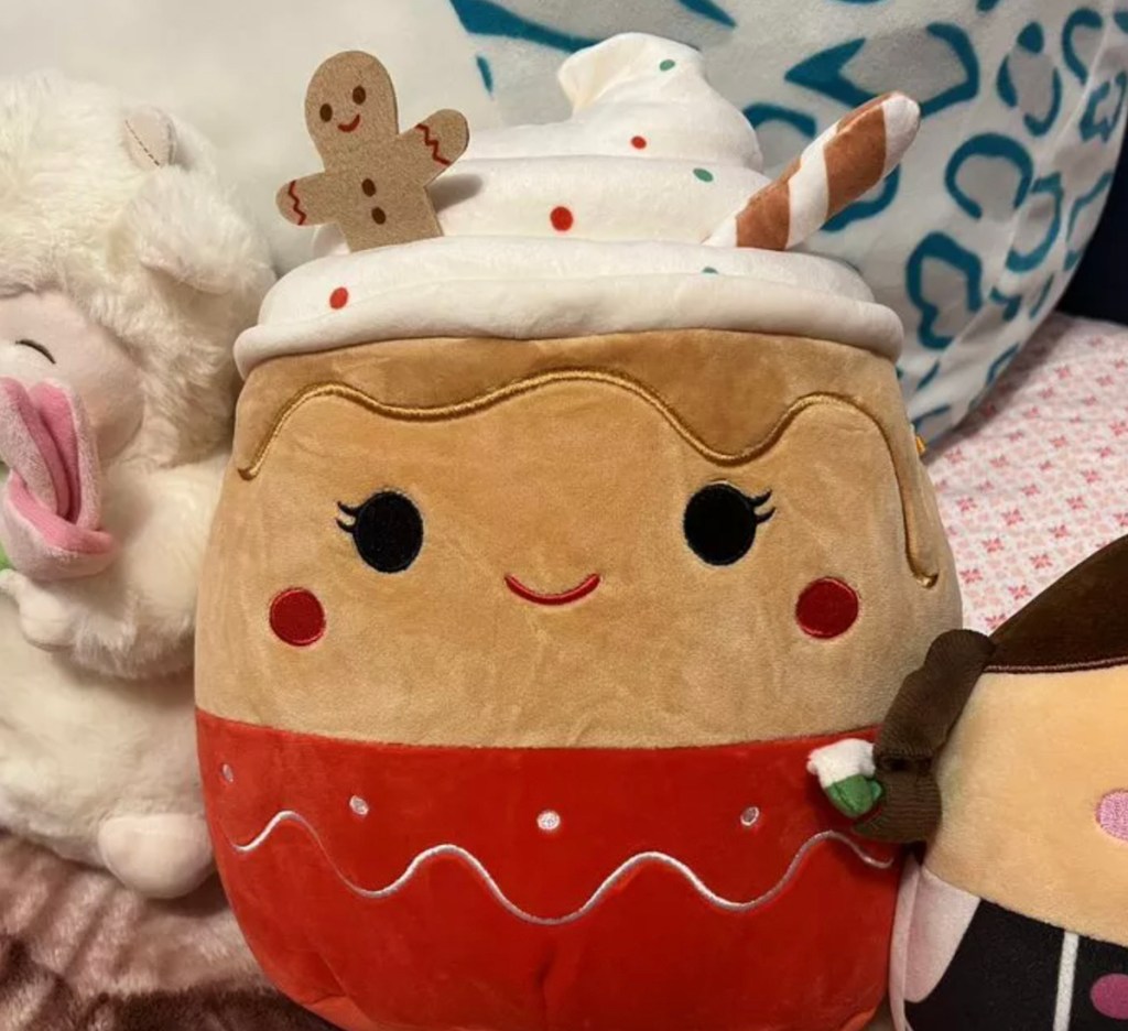 Christmas gingerbread, squishmallow sitting on bed with cool toys