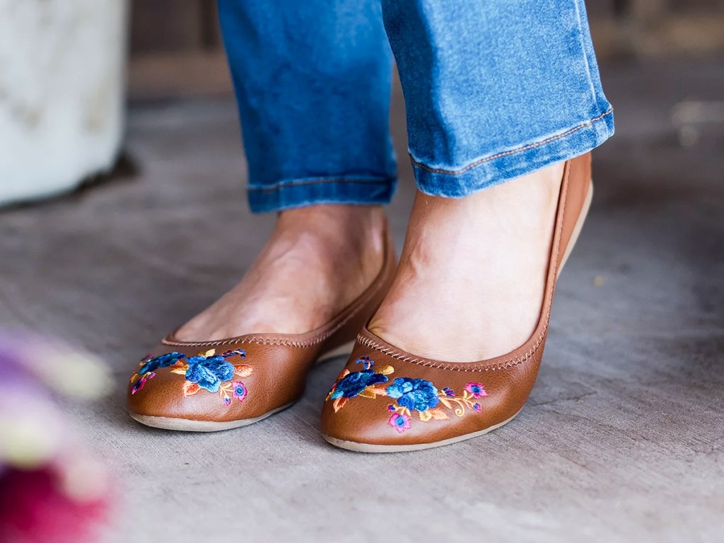 woman in jeans and brown floral embroidered flats
