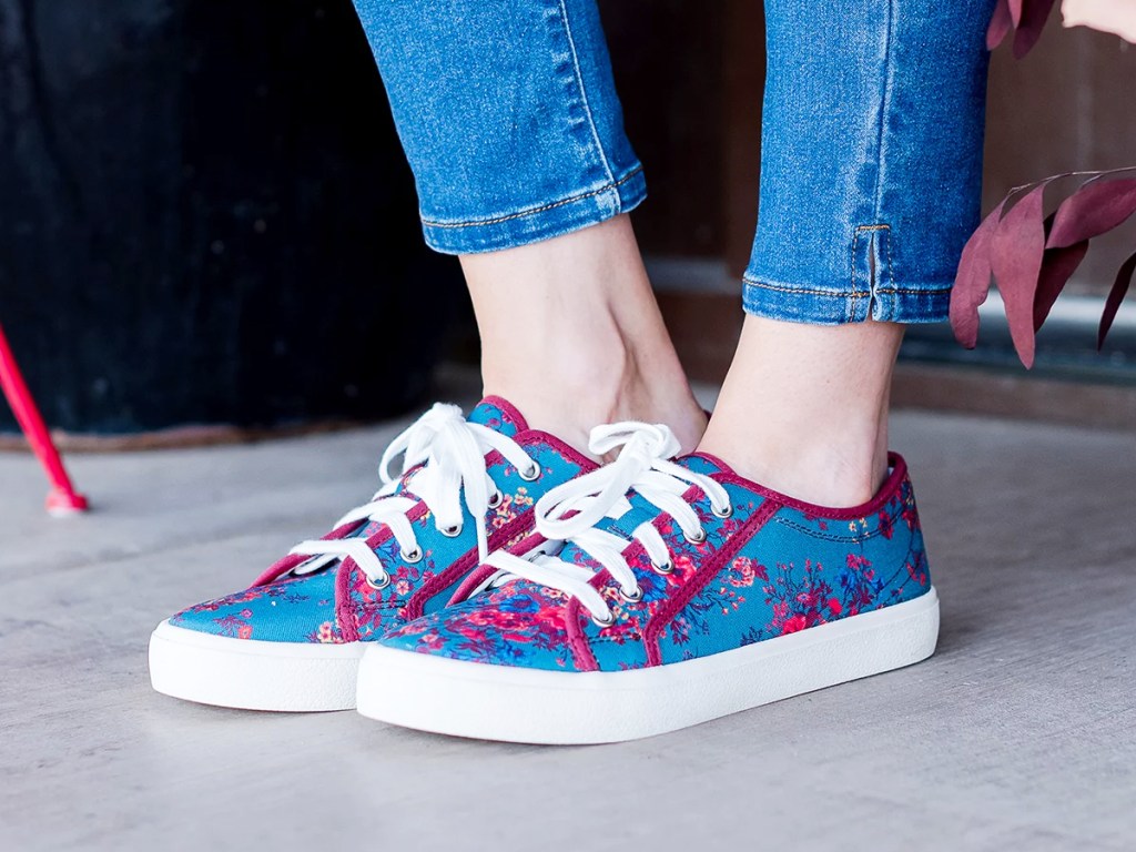 woman in jeans and blue and pink floral print sneakers