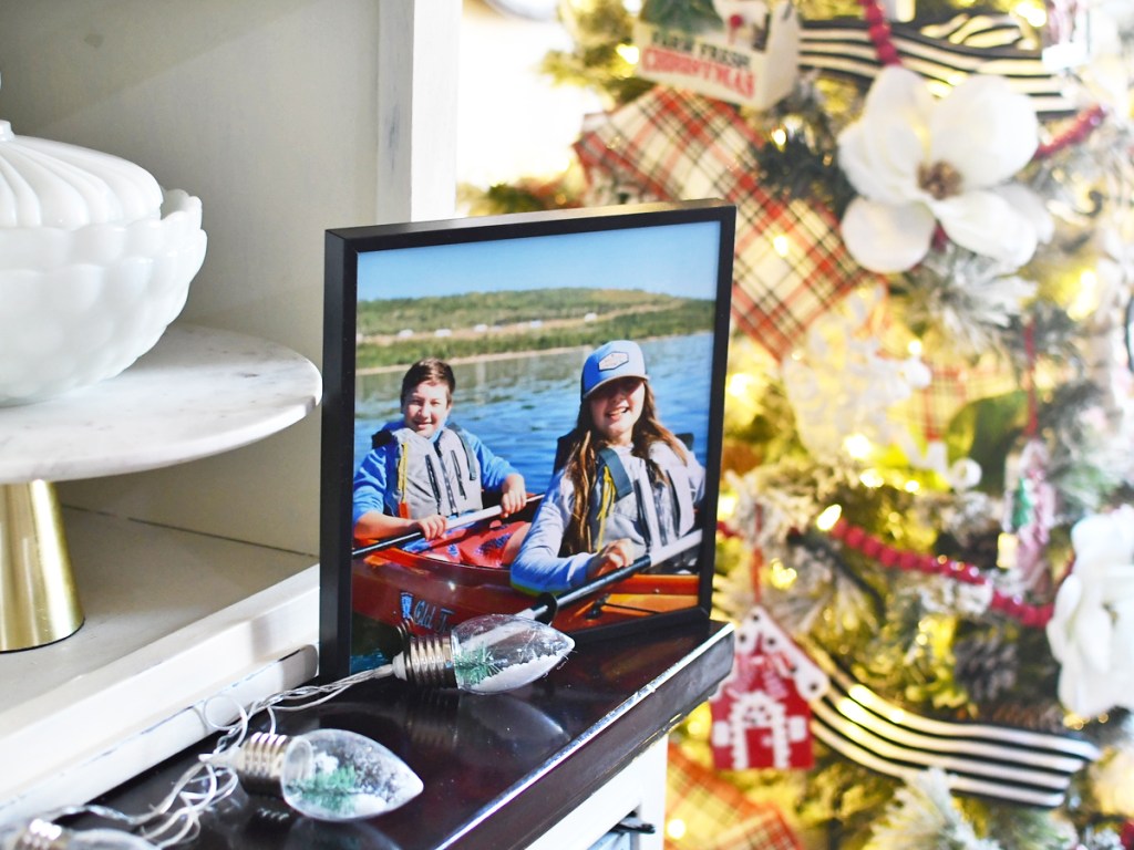 framed photo sitting on a shelf by a Christmas tree