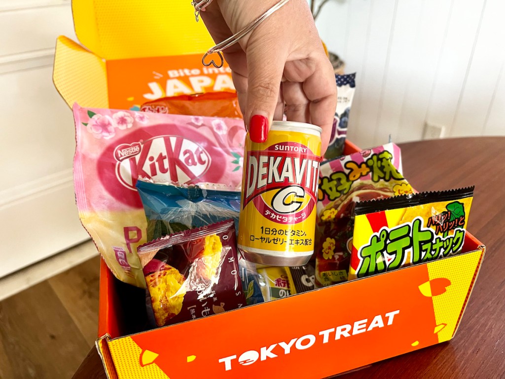 Hand holding Japanese soda from Tokyo treat subscription box on wood table