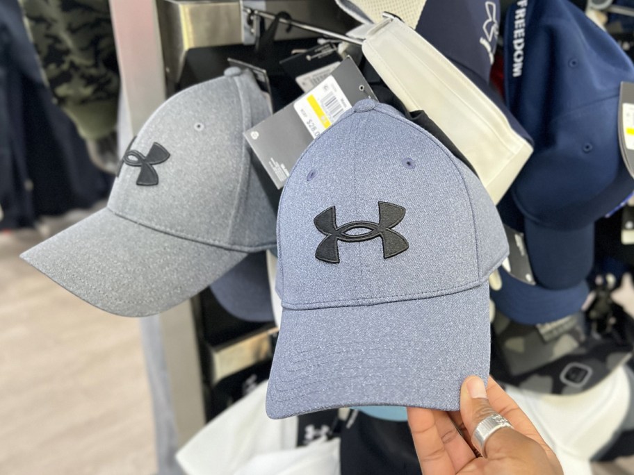 hand touching a light blue under armour hat in store