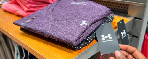 a womans hand displaying the tag attached to an Under Armour women's shirt