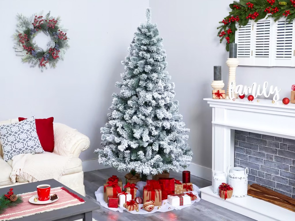 white flocked christmas tree with presents under it in living toom