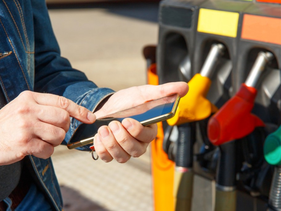 person holding a phone near gas pump
