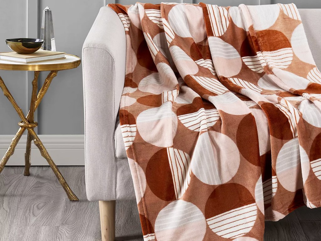 brown throw blanket with circle print draped over grey couch